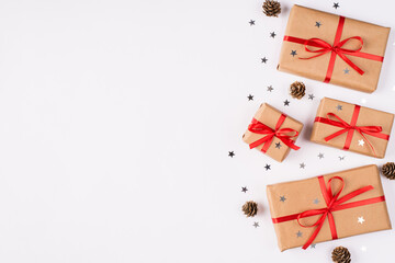 Christmas flat lay layout background with wrapped in kraft paper present boxes silver confetti and spruce cones isolated over white