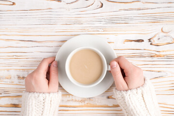 Top close up above overhead photo of female hands holding cup of aromatic morning coffee over wooden background