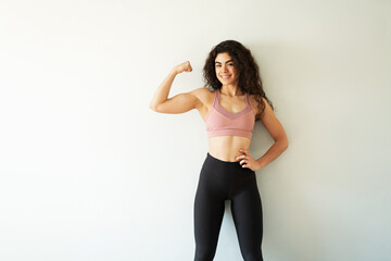 Portrait of a happy woman in her 20s doing a bicep pose