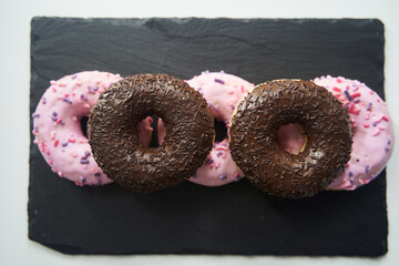 sweet glazed pink donuts close-up on a black tray.