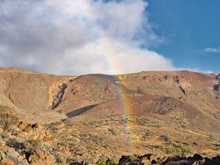 Bizarre lava rock formations in the colors violet, green, blue and red. in the National Park Teide at 2300 m altitude. In the foreground a fresh Rainbow.