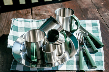 stainless steel camping and picnic utensils on a wooden table, utensils cutlery, dishes
