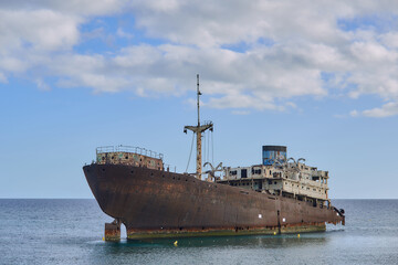The stranded ghost ship. The ship crashed against the coastal rocks. Rusty boat on the seashore in...