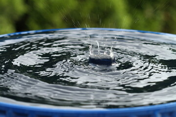 Wassertropfen tropfen in eine Wassertonne und spritzen