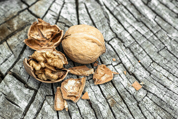 Whole and broken walnuts on cracked wooden background. Walnuts with open and close kernels.