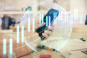 Double exposure of man's hands holding and using a digital device and forex graph drawing. Financial market concept.