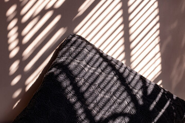 Knitted pillow with blind shadows on the wall. Knitted pillow with jalousie shadows. Winter cozy...