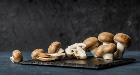 Fresh champignon mushroom slices and whole mushrooms on the granite plate.