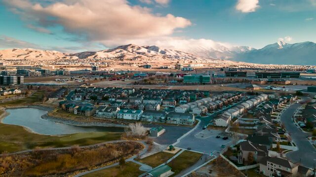 Aerial hyperlapse of a snowy mountain community with a train passing and a dynamic cloudscape