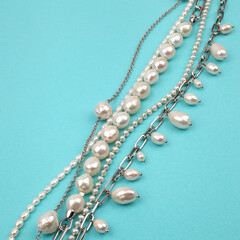 Closeup shot of luxury elegant baroque pearl necklace on bright turquoise textured background