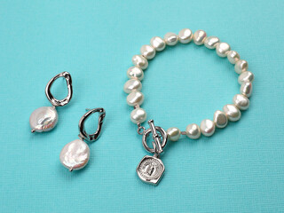Luxury elegant baroque pearl earrings and bracelet on bright turquoise textured background