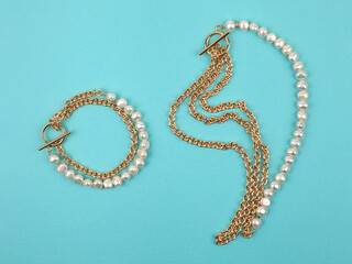 Luxury elegant baroque pearl necklace and bracelet on bright turquoise textured background