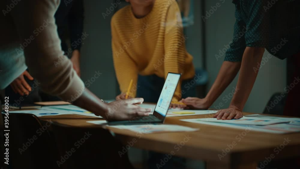 Aufkleber Close Up of Diverse Multiethnic Team Having Conversation in Meeting Room in a Creative Office. Colleagues Lean On a Conference Table, Look at Laptop Computer and Make Notes with Pencils on Notebooks.