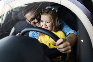 Father and daughter buying a new car at the car showroom.