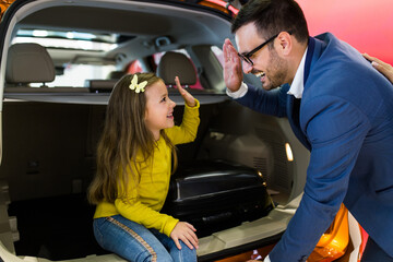 Father and daughter buying a new car at the car showroom.