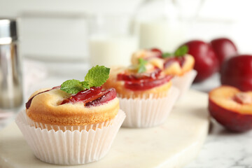 Delicious cupcakes with plums on white board, closeup