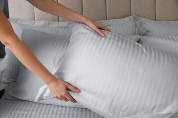 Woman putting soft pillow on bed, closeup