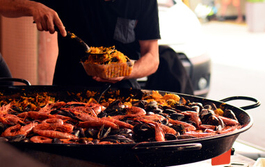 Paella de mariscos, mujer sirviendo paella de mariscos para llevar en un mercado