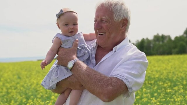 A Happy grandparents with little baby granddaughter enjoying moment in beautiful yellow field