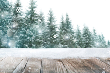 Fototapeta premium Wooden board with snow and blurred forest on background. Christmas time