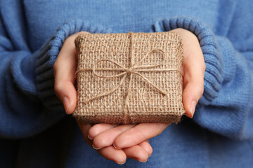 Woman in blue sweater holding Christmas gift box, closeup