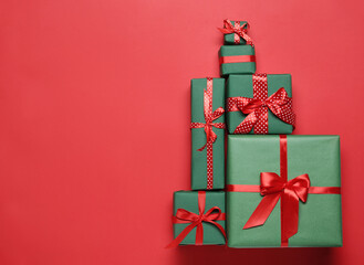 Christmas tree shape of gift boxes on red background, flat lay. Space for text