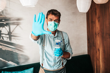 Fototapeta na wymiar Handsome middle age waiter cleaning and disinfecting restaurant table for next customer. Corona virus and small business is open for work concept..