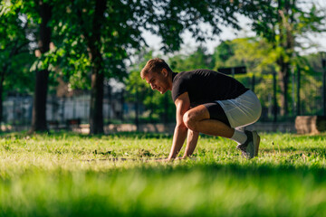 Fototapeta na wymiar Sporty young man practicing crow pose or bakasana, yoga asana, outdoors in a park
