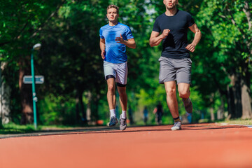 Two healthy young men running in the park on a sunny day..