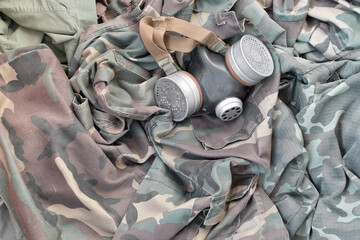 Stalker soldiers soviet gas mask lies on many green khaki camouflage jackets