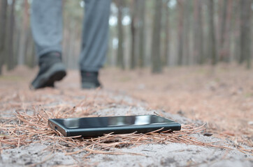 Young man loses his smartphone on Russian autumn fir wood path. Carelessness and losing expensive...