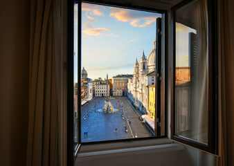 Early morning view from an open window overlooking Piazza Navona as sunlight lights the dome on the...