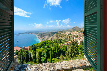 View through an open window with shutters of the beach coastline and village of Taormina Italy, on the island of Sicily © Kirk Fisher