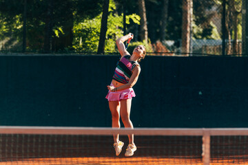 Professional equipped female tennis player serving the tennis ball on a sunny day