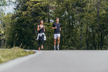Fototapeta premium Young fit couple atheltes running on running road in a forest.