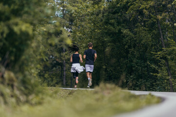 Obraz premium Young fit couple atheltes running on running road in a forest.