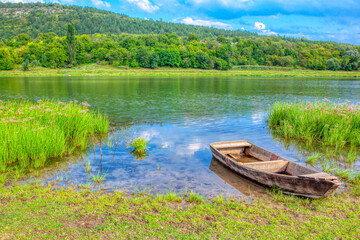 Idyllic green scenery with wooden boat . Spectacular riverside nature 