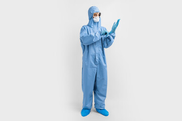 Full-length male doctor in protective clothing, glasses, mask and gloves, on a white background, coronavirus epidemic concept