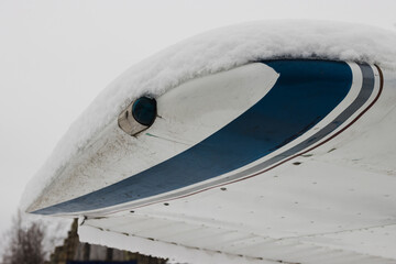 Part of the wing of a small private plane covered in snow, winter at the airfield.