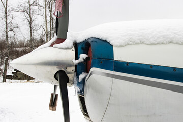 Gray blade, the hood of a small private plane covered with snow, winter in bad weather at the airport.