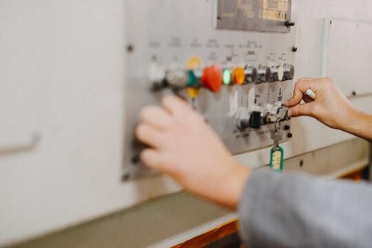 Closeup shot of hands operating colorful knobs and buttons on an industrial machine
