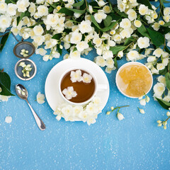 Healthy Herbal Flower tea. Tea cup with Jasmine Flowers on blue grunge textured background. Herbal Medicine. White Spring Flowers
