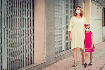 Woman and daughter wearing facial disposable mask. Coronavirus protection