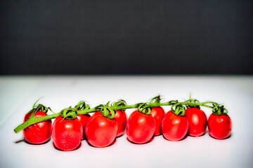 Cherry tomatoes on white table and black background	