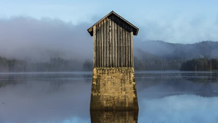 Tiny old wooden cabin in middle of tranquil lake covered in thick fog - Powered by Adobe