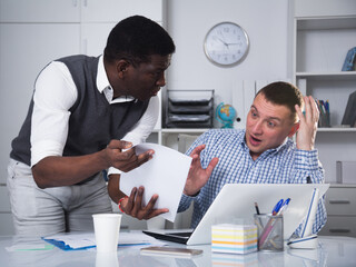 African American businessman feeling discontent with male coworker in office, pointing out mistakes...