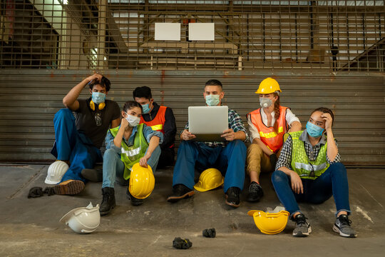 Group Of Factory Workers Wearing Protective Face Mask Saddened After News Of The Coronavirus's Impact On The Economy And Layoffs.