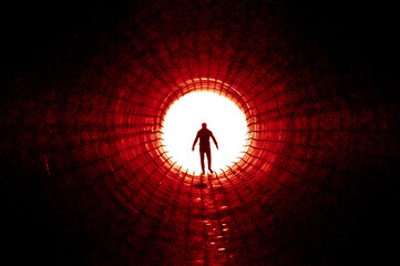 Silhouette of a man walking to the light at the end of a big tunnel. Concept of escape, exit, freedom, clinical death