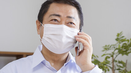 マスクをつけてスマホを操作する中高年の男性