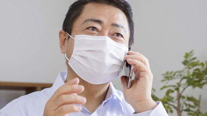 マスクをつけてスマホを操作する中高年の男性